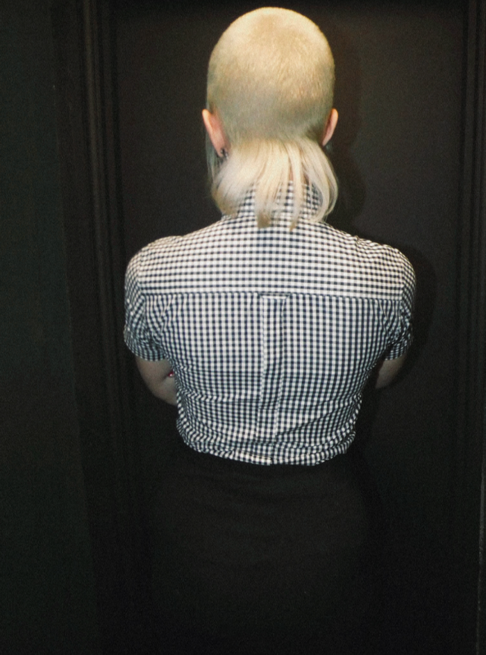 Person wearing a black and white checkered shirt against a dark background