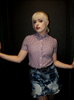 Person wearing a checkered shirt and denim skirt against a dark background